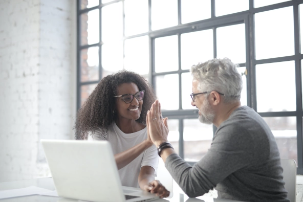 Coach and client celebrating a successful session with a high-five in a bright, modern office, symbolizing teamwork, motivation, and positive coaching outcomes.