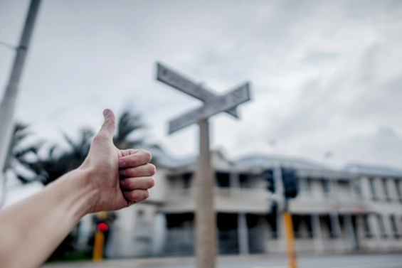 Thumbs up gesture near a crossroads signpost, symbolizing guidance, direction, and the positive impact of coaching in navigating decisions and overcoming challenges.