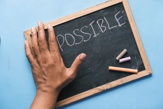 Hand on a chalkboard with the word 'Possible' written, symbolizing confidence and the potential for positive outcomes in a coaching relationship.