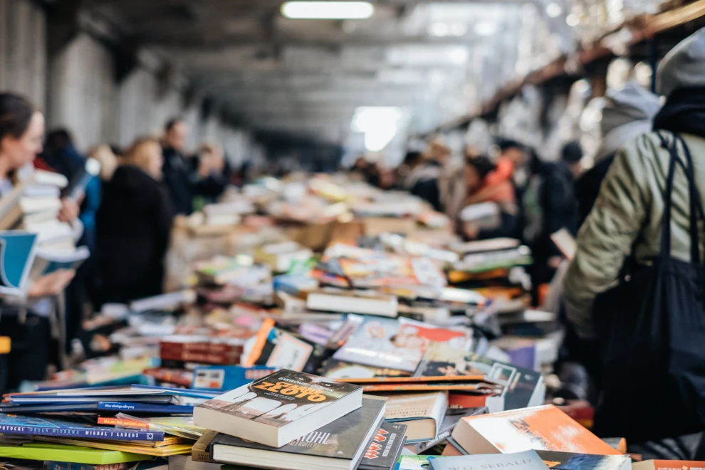 Busy book market filled with various books and people browsing, symbolizing the abundance of knowledge and the search for guidance, reflecting the value of coaching in navigating life's challenges.